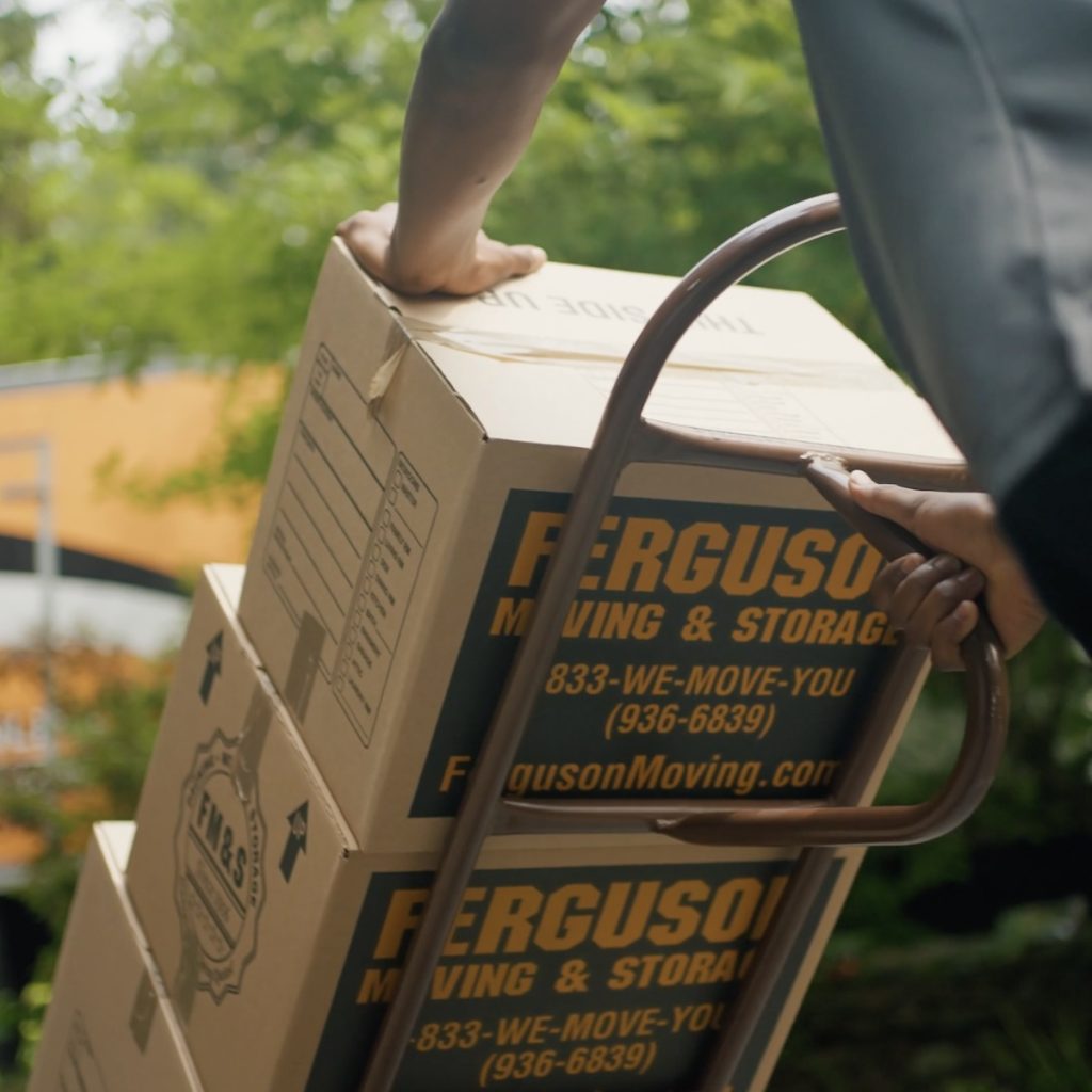A Ferguson mover carries packed moving boxes to a truck.