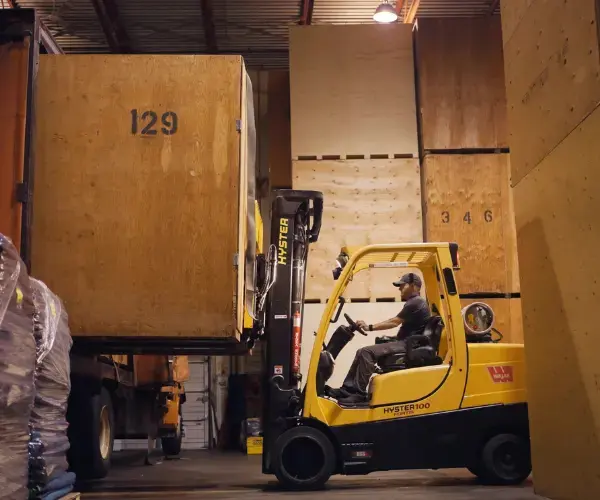 Man driving forklift in a Ferguson Moving & Storage warehouse.