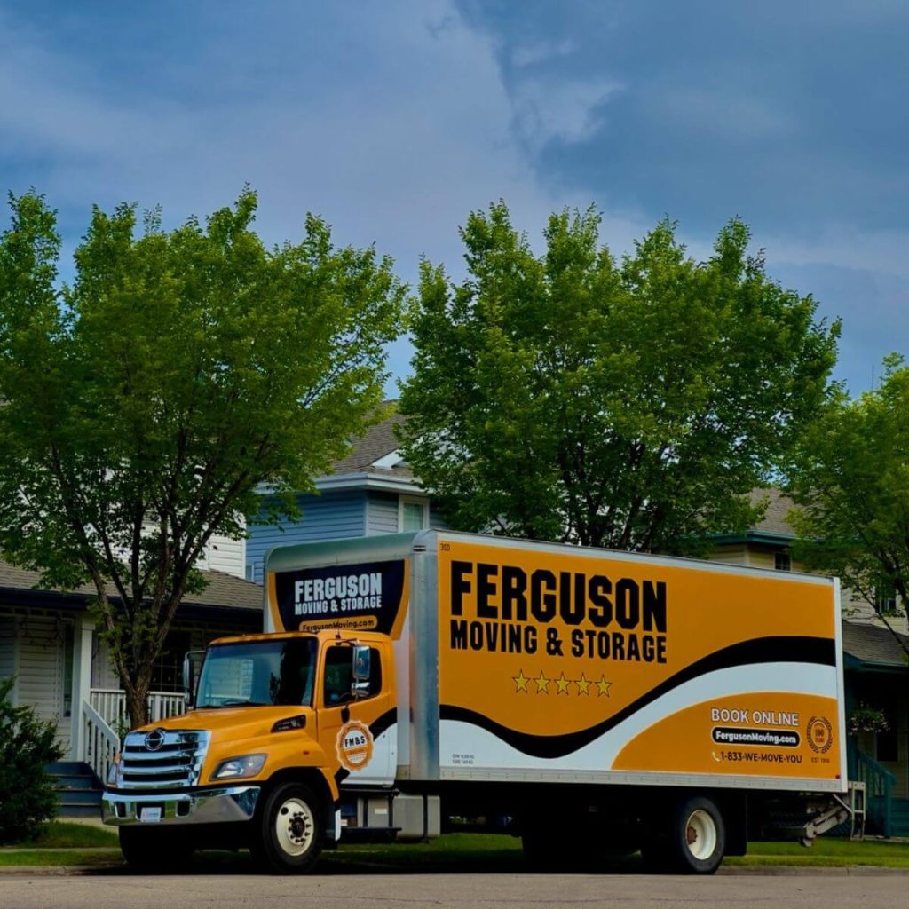 Moving truck parked by a house in a residential neighbourhood.