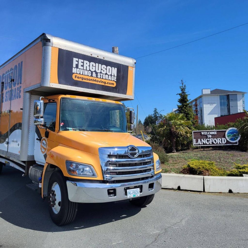 A Ferguson moving truck is stationed beside a Welcome to Bradford sign.