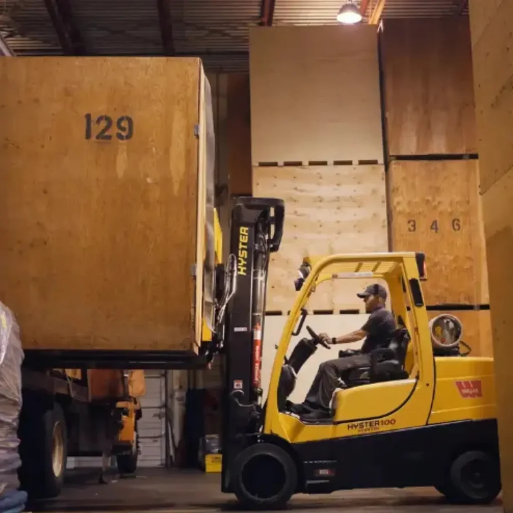 A ferguson moving employee on a forklift moving a storage crate.
