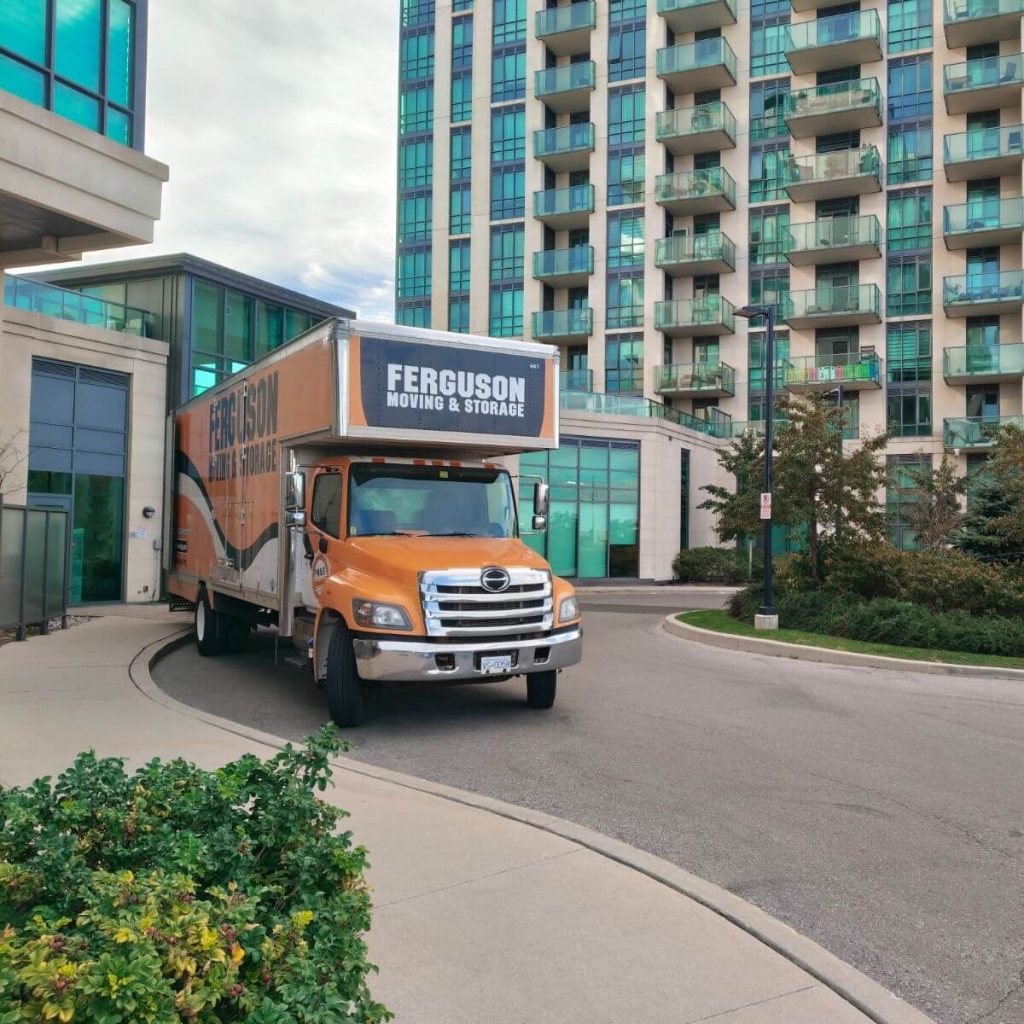 Front angle of the orange Ferguson moving truck pulled into a condo building's circular entrance