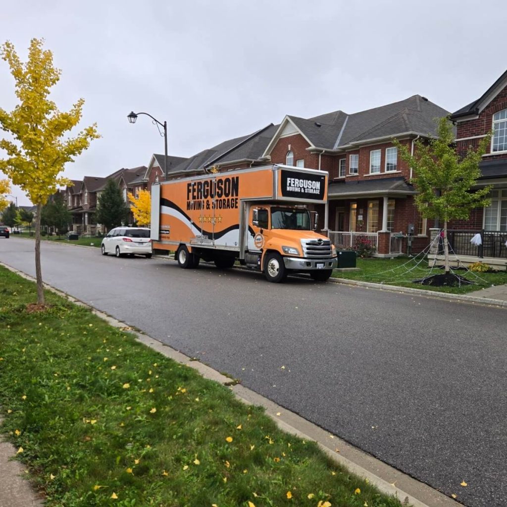 Ferguson moving truck parked along a street of red-brick townhomes in East Gwillimbury, young trees turning yellow for fall