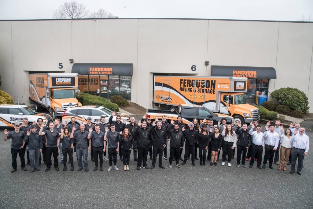 Ferguson Moving & Storage movers and office staff waving in front of our moving trucks at the North Vancouver location